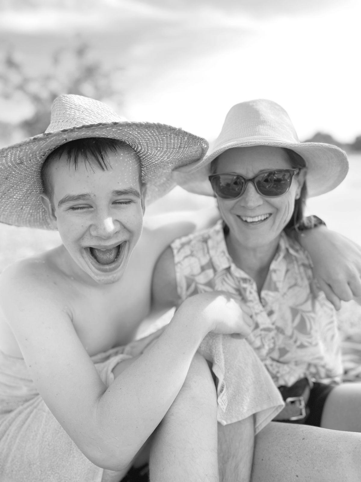 Alison Blair and her son Ewan smiling together in sun hats, photographed in black and white.