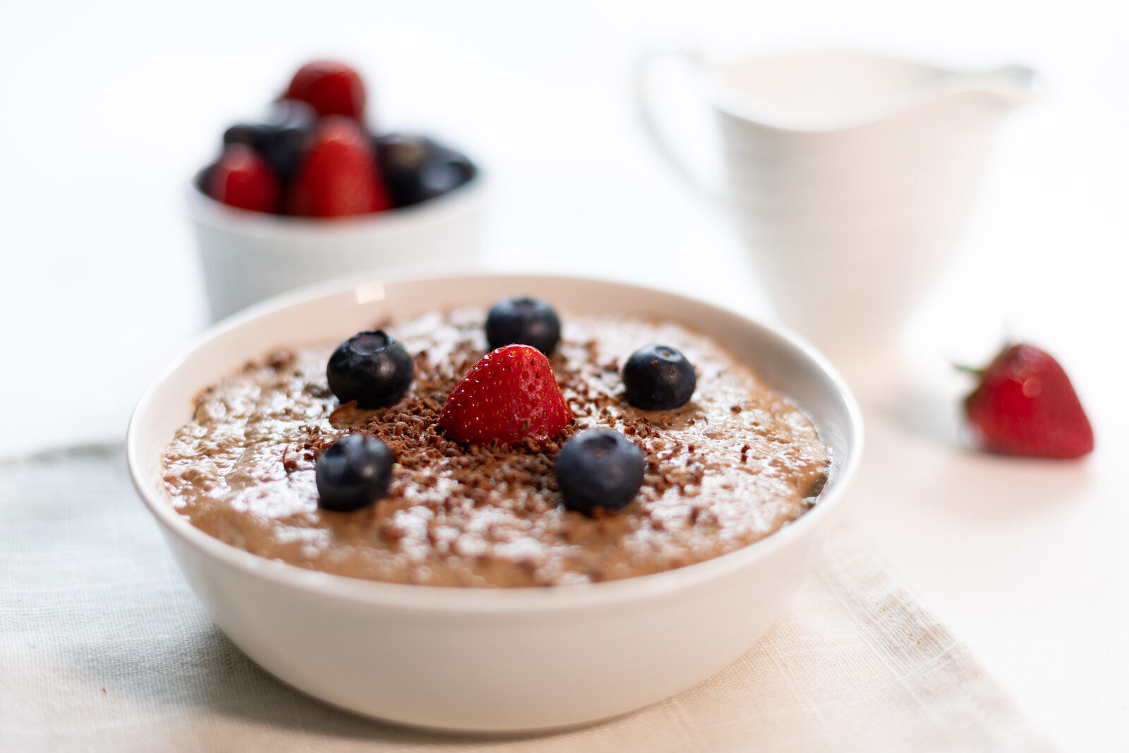 A bowl of Power Porridge with fresh berries beside the kraft pouch.